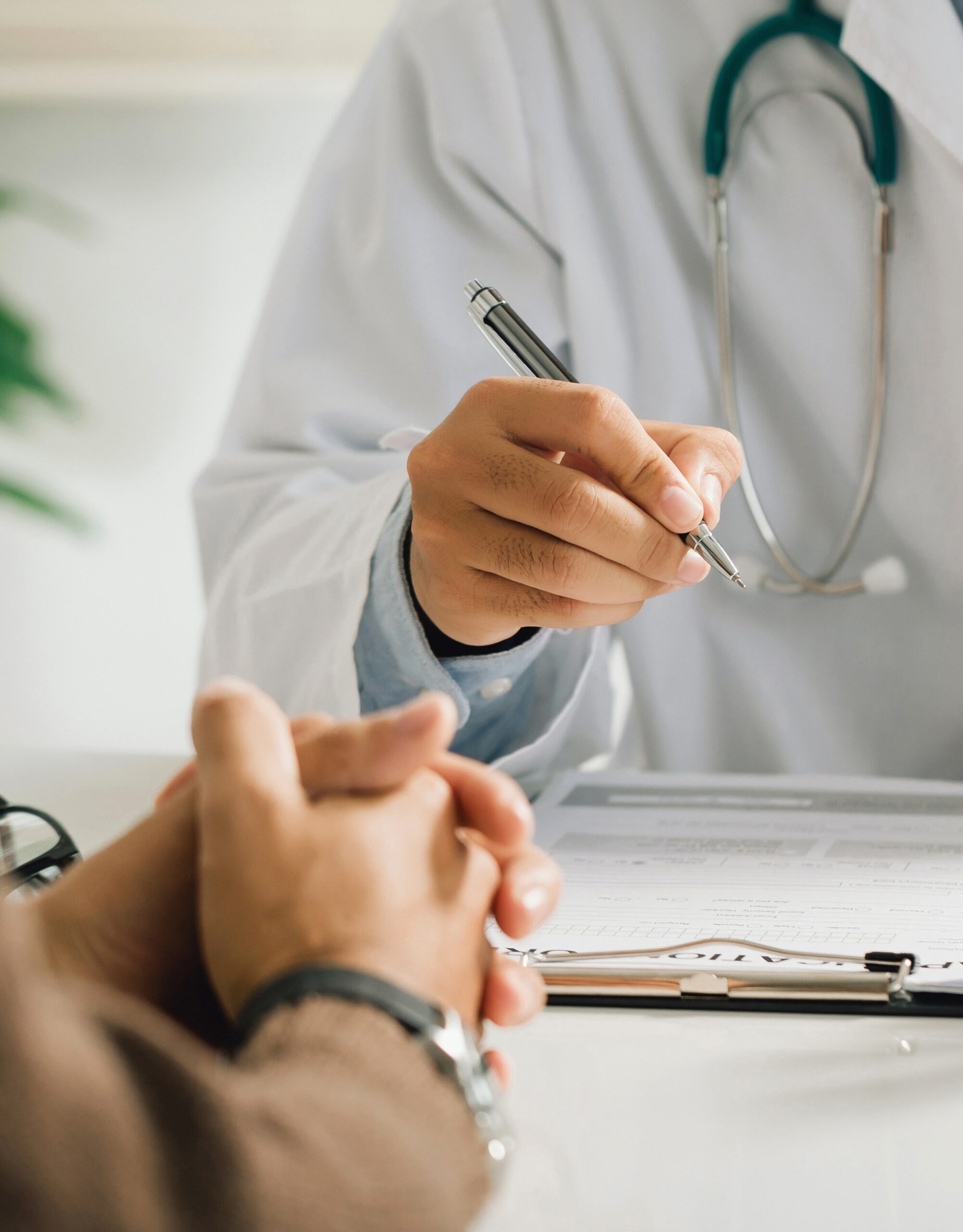 A professional physician in a white medical uniform talks to discuss results or symptoms and gives a recommendation to a male patient and signs a medical paper at an appointment visit in the clinic.